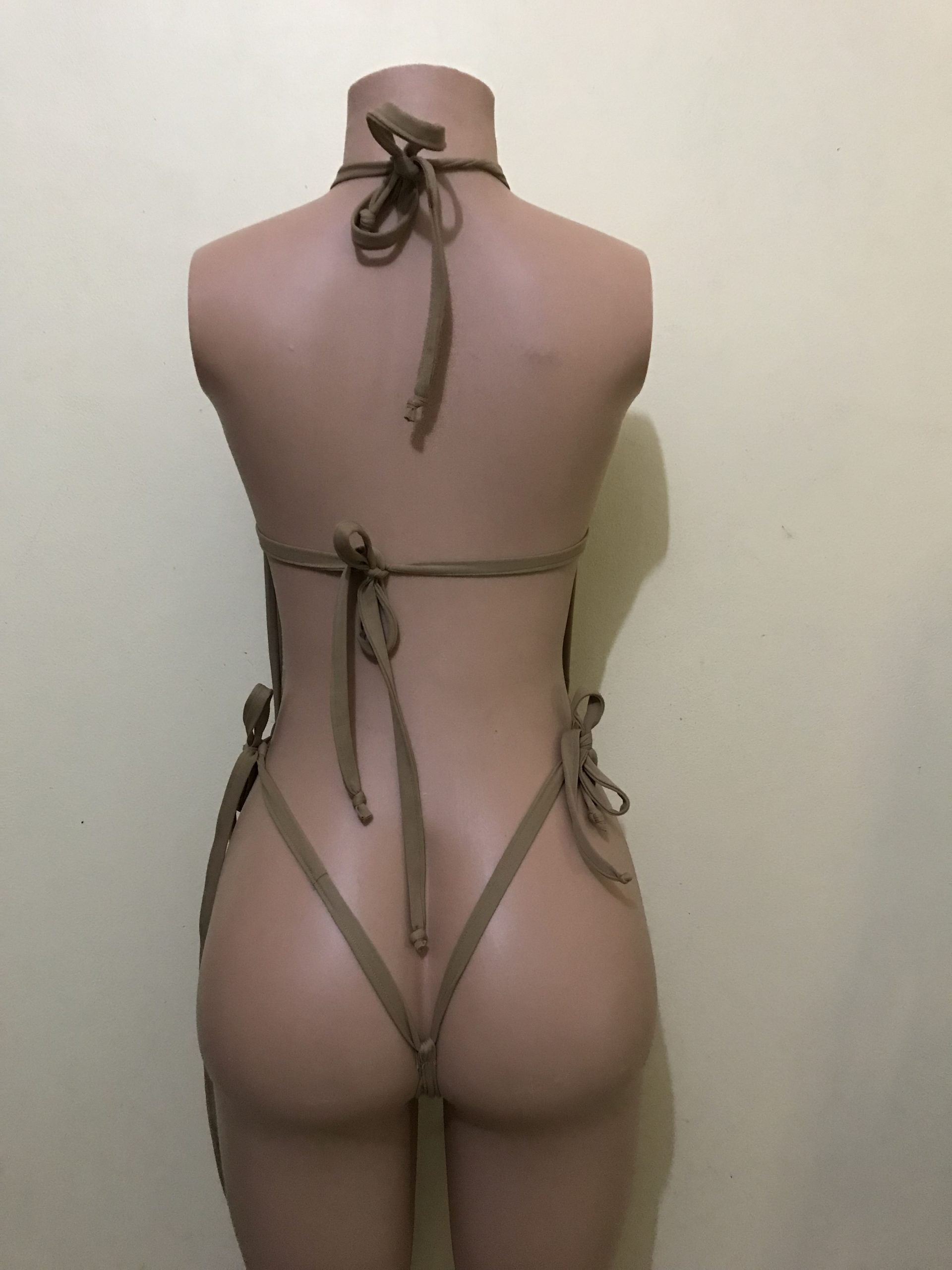 Nude mesh halter monokini with tie-back straps and thong bottom, back view on mannequin