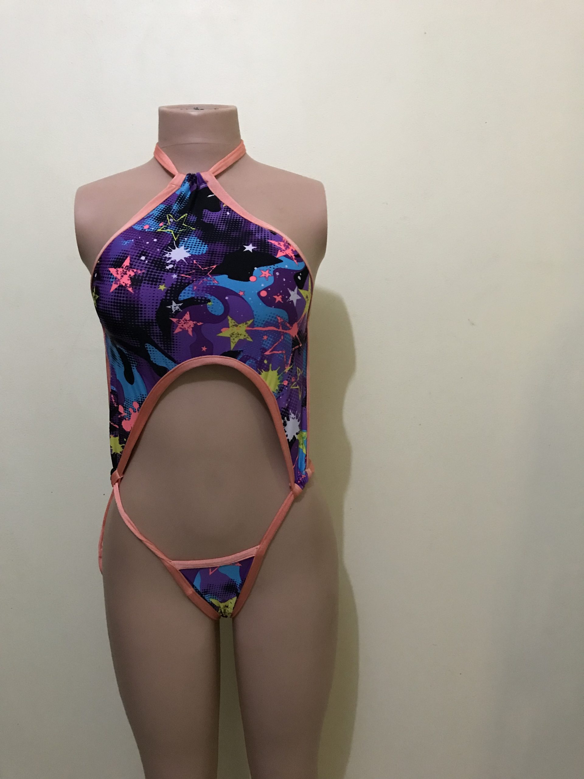 Multicolor star-print monokini with coral trim and cut-out, front view on mannequin